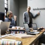 オフィスでの研修中に重要ポイントを解説する講師とそれを聞く外国人労働者たち