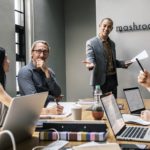 オフィスでの研修中に男性講師に対して質問をする女性