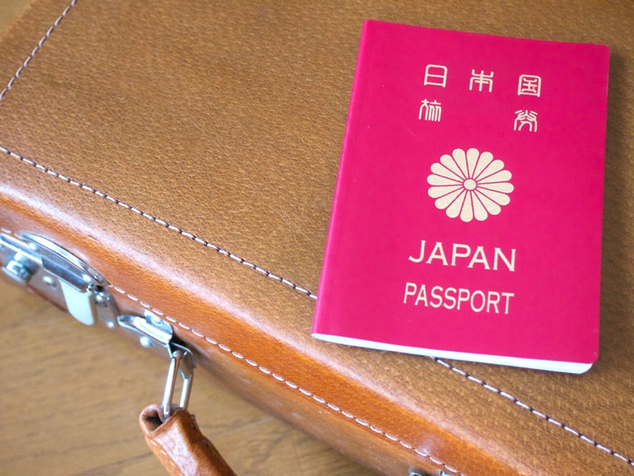 茶色の鞄の上に置かれた日本国籍のパスポート