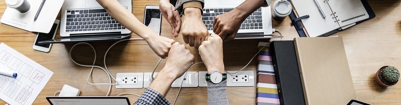 チームとして働く人達が拳を合わせて結束を誓っている