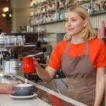 顧客に飲み物を入れるカフェの外国人店員