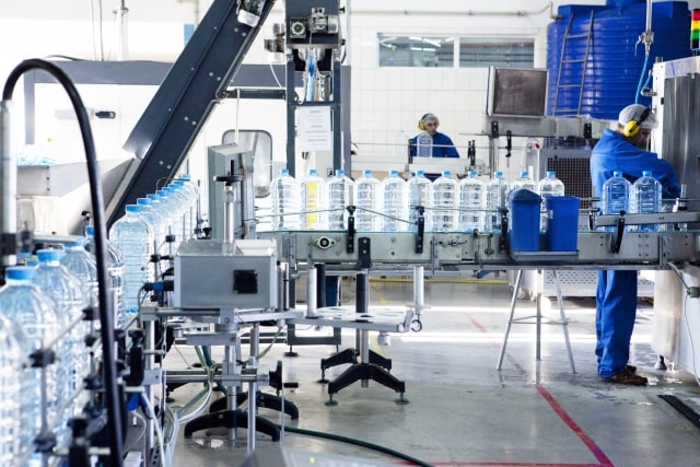 工場内のラインで機械を操作する労働者