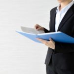 ファイルを片手に何かを検討しているスーツ姿の女性