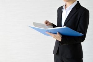 ファイルを片手に何かを検討しているスーツ姿の女性