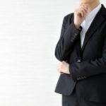 スーツ姿の女性が手を顎にあてて考えている