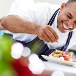 笑顔で料理を盛り付ける外国人シェフ