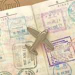 出入国スタンプが押されたパスポートの上に小さな飛行機の模型が置かれている