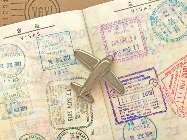 出入国スタンプが押されたパスポートの上に小さな飛行機の模型が置かれている
