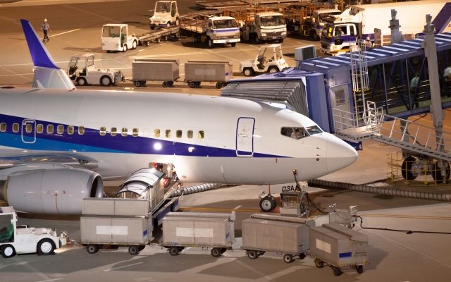 空港で飛行機に荷物搬送車が横付けされている