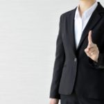 人差し指を立てているスーツ姿の女性