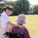 車椅子の老人に笑顔で話しかける女性介護士