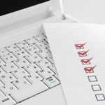 パソコンのキーボードの上に置かれたチェックリスト
