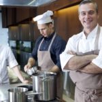 厨房にて笑顔の外国人シェフと作業中のアシスタントシェフたち