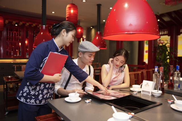 中華レストランで客にメニューを説明する女性店員