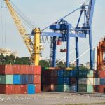 港に設置されたクレーンと積み置かれたコンテナー