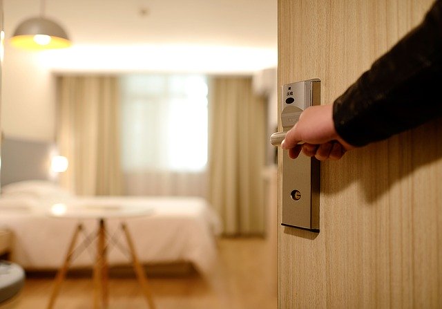 ホテルの部屋のドアを開けて宿泊客を中へ案内するホテルスタッフ