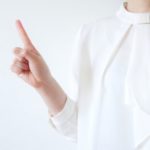 人差し指を立てて注意を促す白い服の女性
