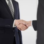 ネクタイをしたスーツ姿の男性が握手している