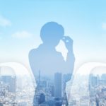 都会の街並みを背景に、2つのルートの間で悩む男性のシルエット