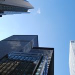 青空を背景に立ち並ぶ高層ビルを下から見上げた様子