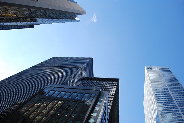 青空を背景に立ち並ぶ高層ビルを下から見上げた様子