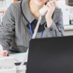 オフィスの机で電話をかけている女性