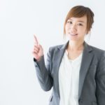 笑顔のスーツ姿の女性が人差し指を立てて注意を促している