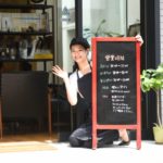 店外に看板を出す笑顔の女性店舗スタッフ