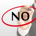 スーツ姿の男性がNOの文字を赤ペンで囲んでいる