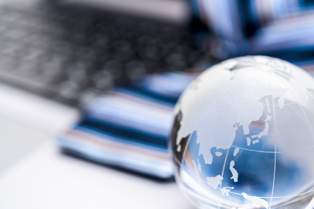 透明な地球儀とパソコンが置かれたデスク