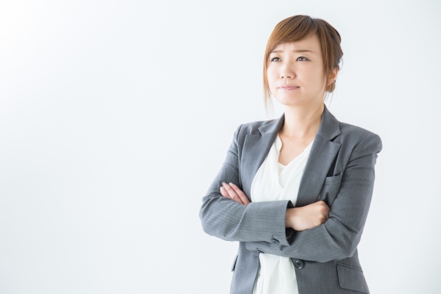 何かを悩んでいる様子のグレーのスーツ姿の女性