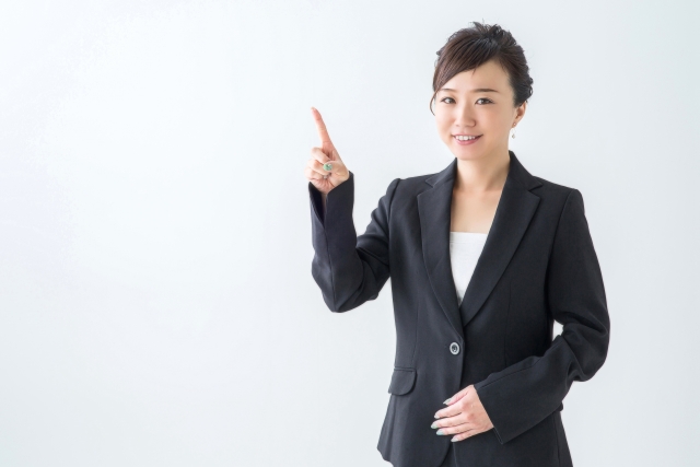 笑顔で何かを指さすスーツ姿の女性
