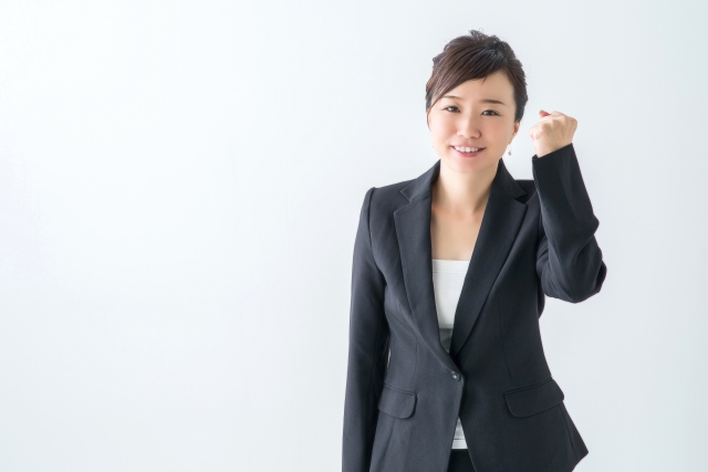 やる気を示すポーズを作っているスーツ姿の女性