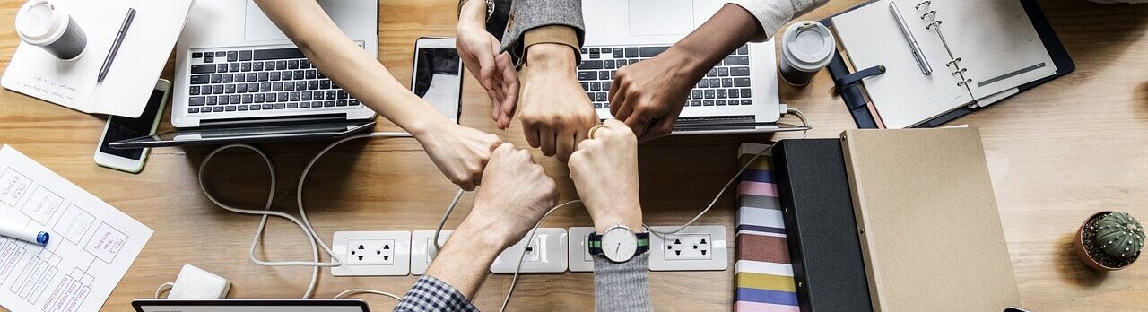 国際色豊かなスタッフが机の上で拳を合わせている